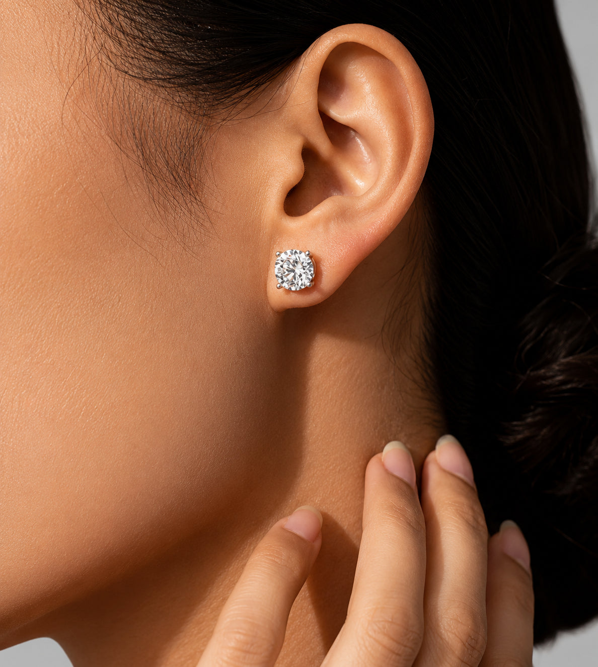Close-up of a larger round moissanite stud earring worn on ear with bright sparkle and elegant look.