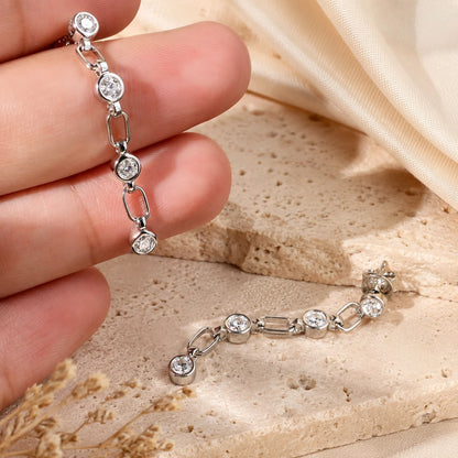 Close-up back view of a Liora 925 sterling silver linear drop earring showing the stud post, butterfly back and linked brilliant-cut stones on a beige surface.