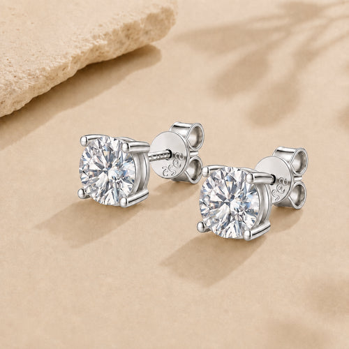 Silver moissanite stud earrings in 925 sterling silver with round brilliant stones on a soft neutral background.
