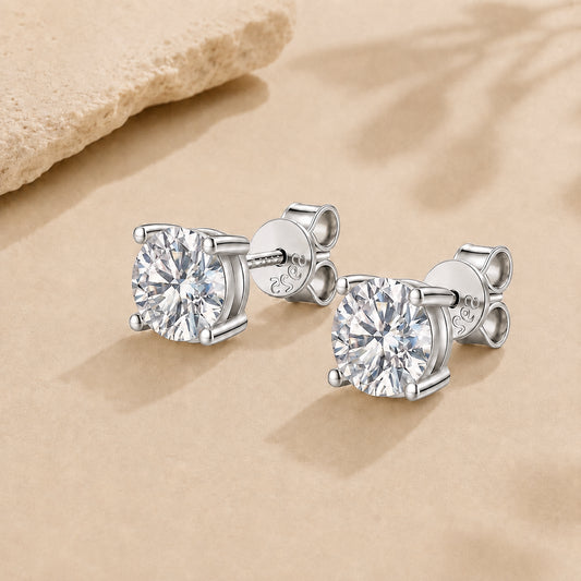 Silver moissanite stud earrings in 925 sterling silver with round brilliant stones on a soft neutral background.