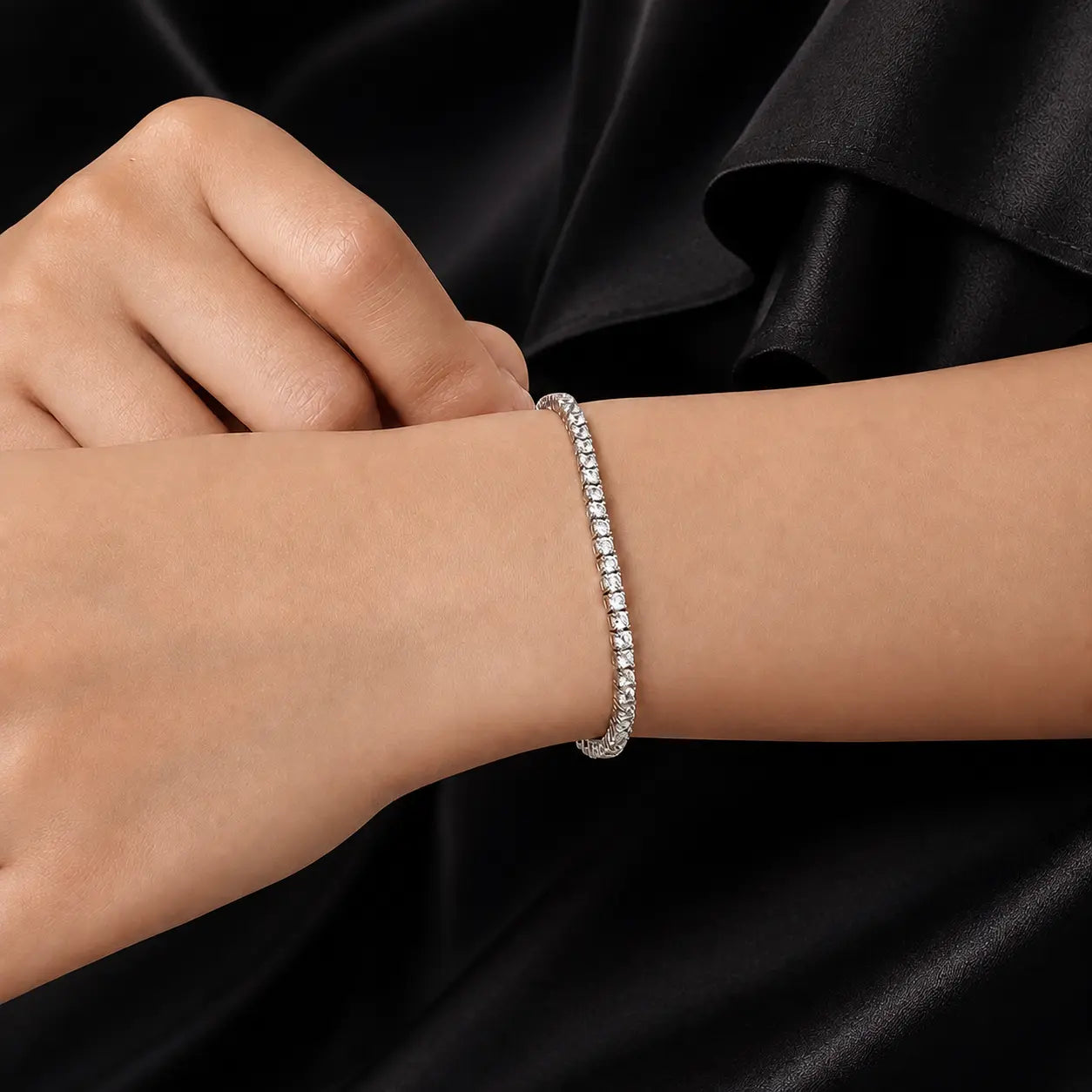 Woman wearing a Cirelle™ round moissanite tennis bracelet with a black sleeve for an elegant evening look.