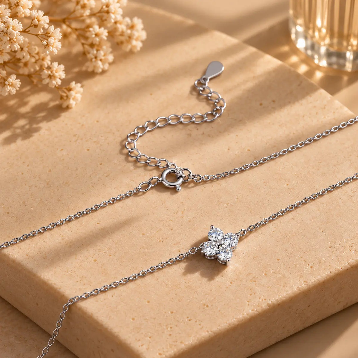 Delicate clover pendant necklace arranged in a warm beige flat lay setting