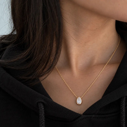 Woman wearing a delicate pear moissanite necklace with a casual black outfit