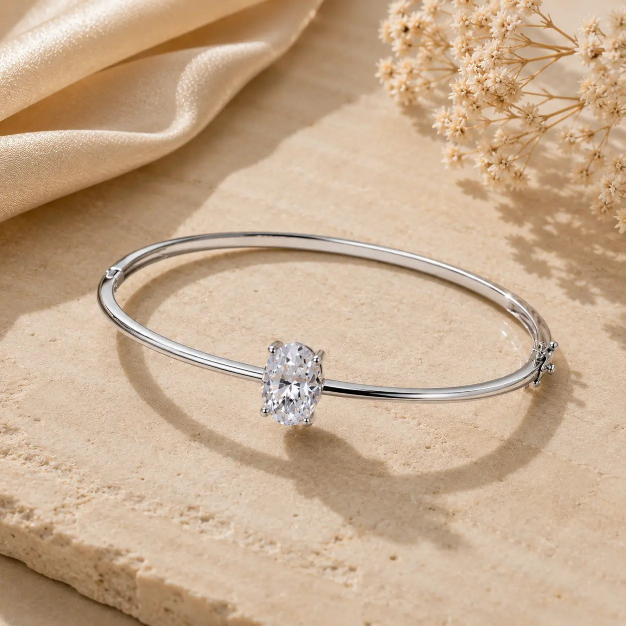 Silver 2CT oval-cut moissanite bangle bracelet for women displayed on a warm beige stone surface.