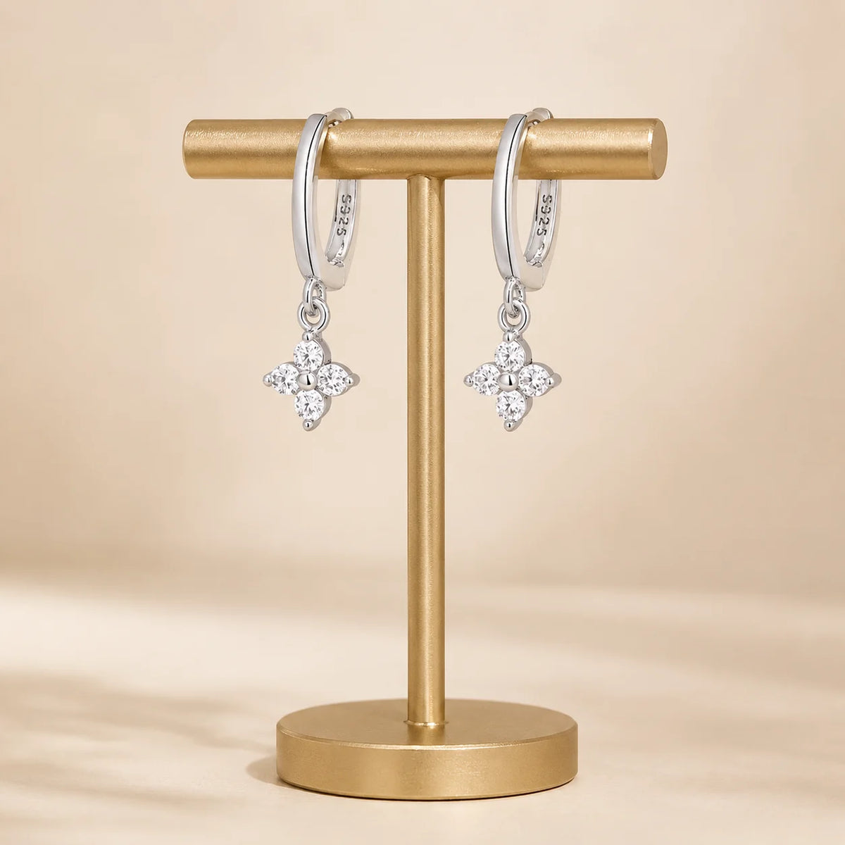 Pair of Clovera™ Clover Moissanite Hoop Drop Earrings displayed on a minimalist gold jewelry stand.