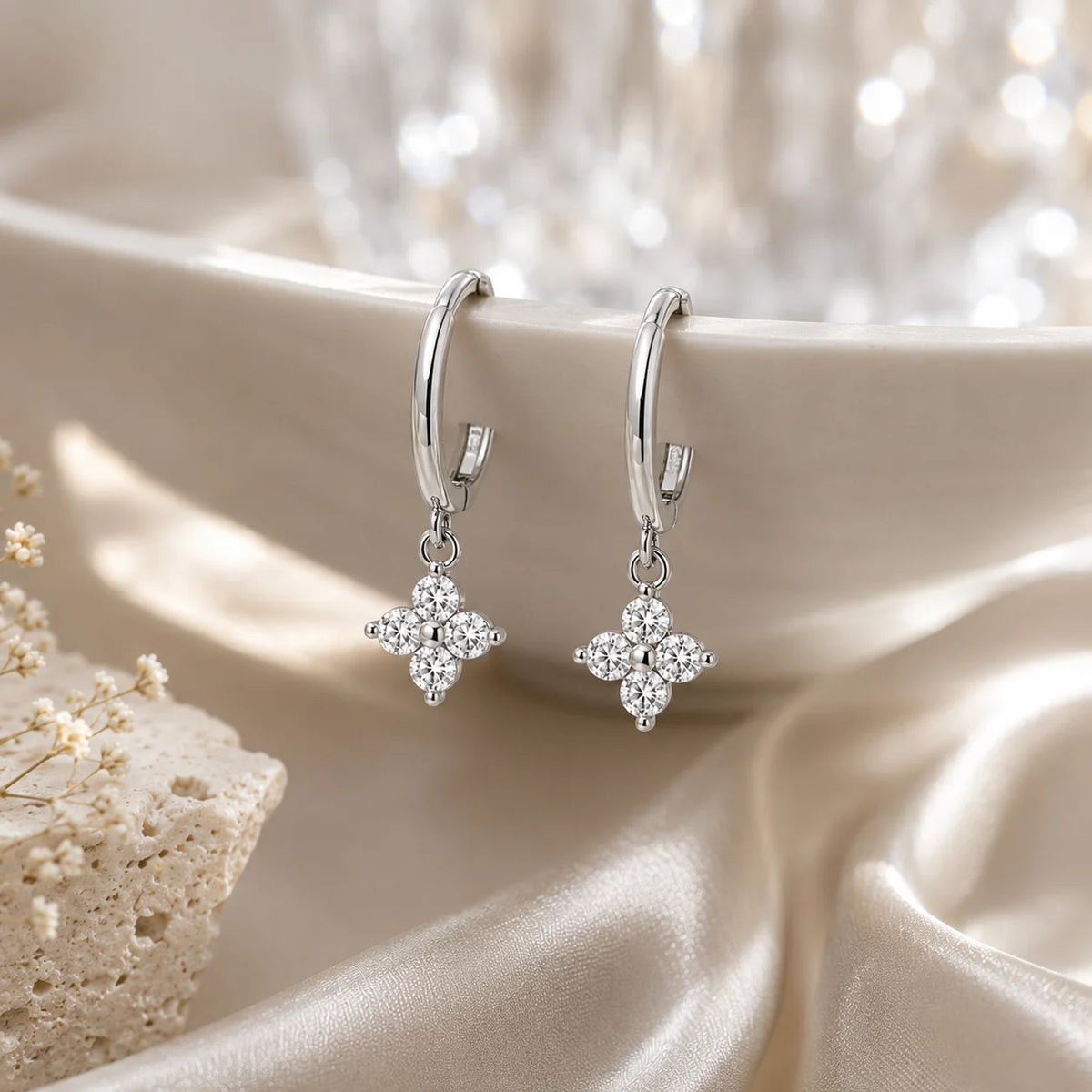 Clovera™ Clover Moissanite Hoop Drop Earrings arranged on soft satin with a warm luxury background.