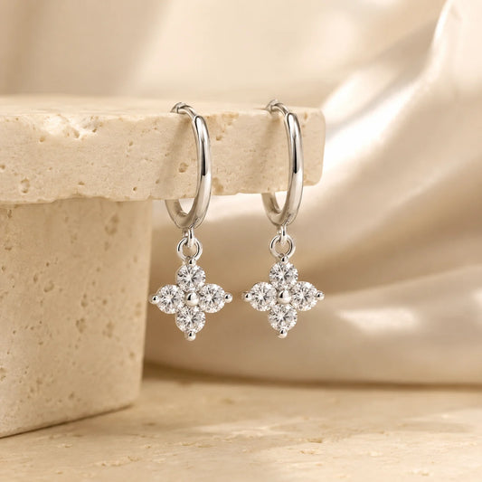 Side view of Clovera™ Clover Moissanite Hoop Drop Earrings displayed on a warm beige stone surface.