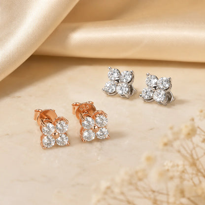 Elaris™ Four-Petal Moissanite Stud Earrings shown in silver and rose gold finishes on a warm beige display.