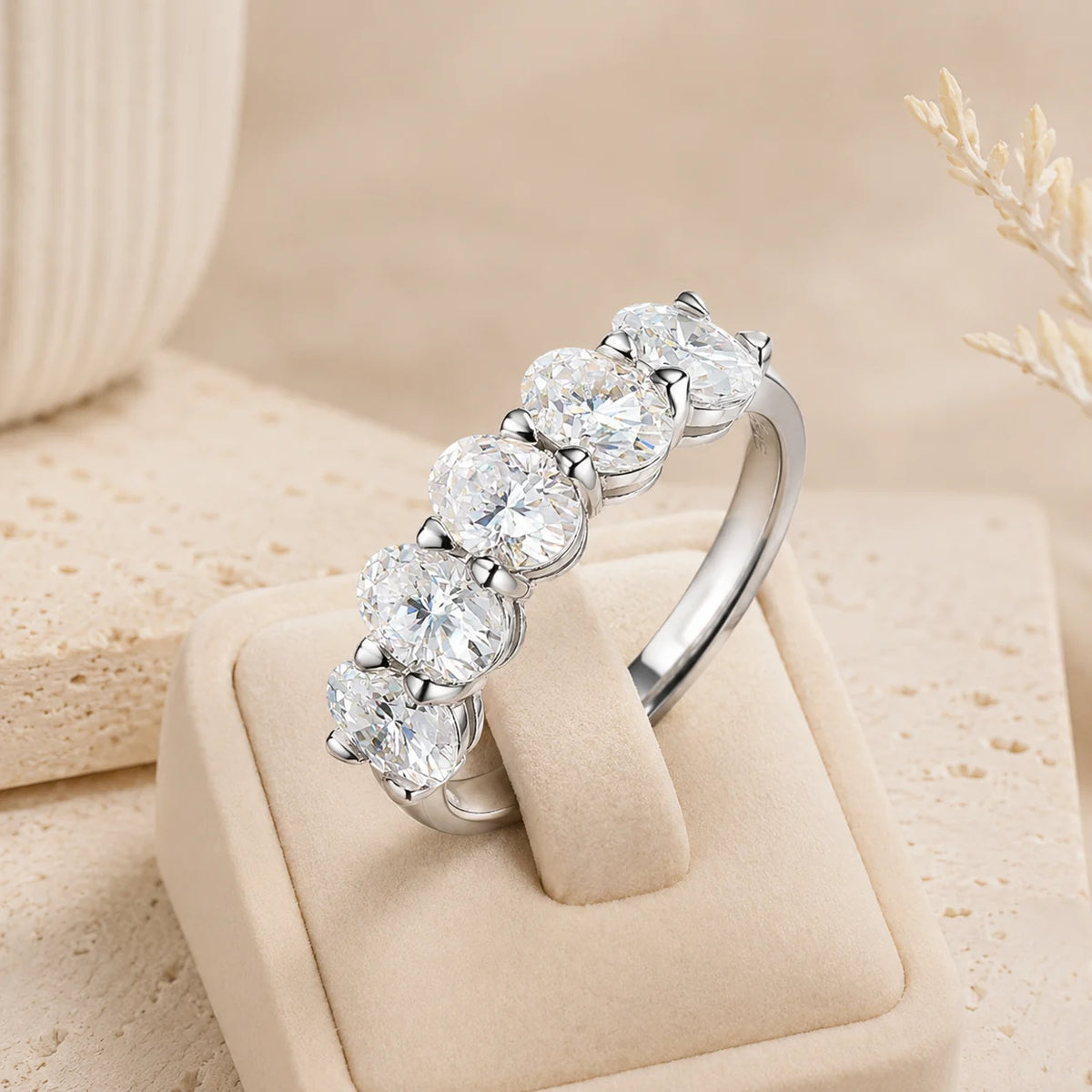 Angled view of a silver five-stone moissanite anniversary band with brilliant stones in classic prong settings.
