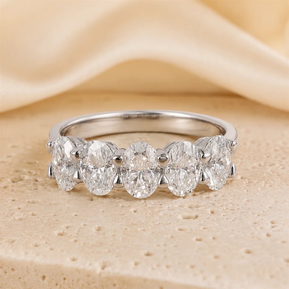 Front view of a five-stone oval-cut moissanite ring featuring brilliant graduated stones in a polished sterling silver setting.