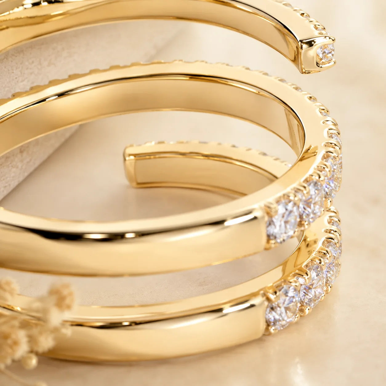 Close-up side view of a gold three-row moissanite wrap ring showing its polished open-band design and stone settings.