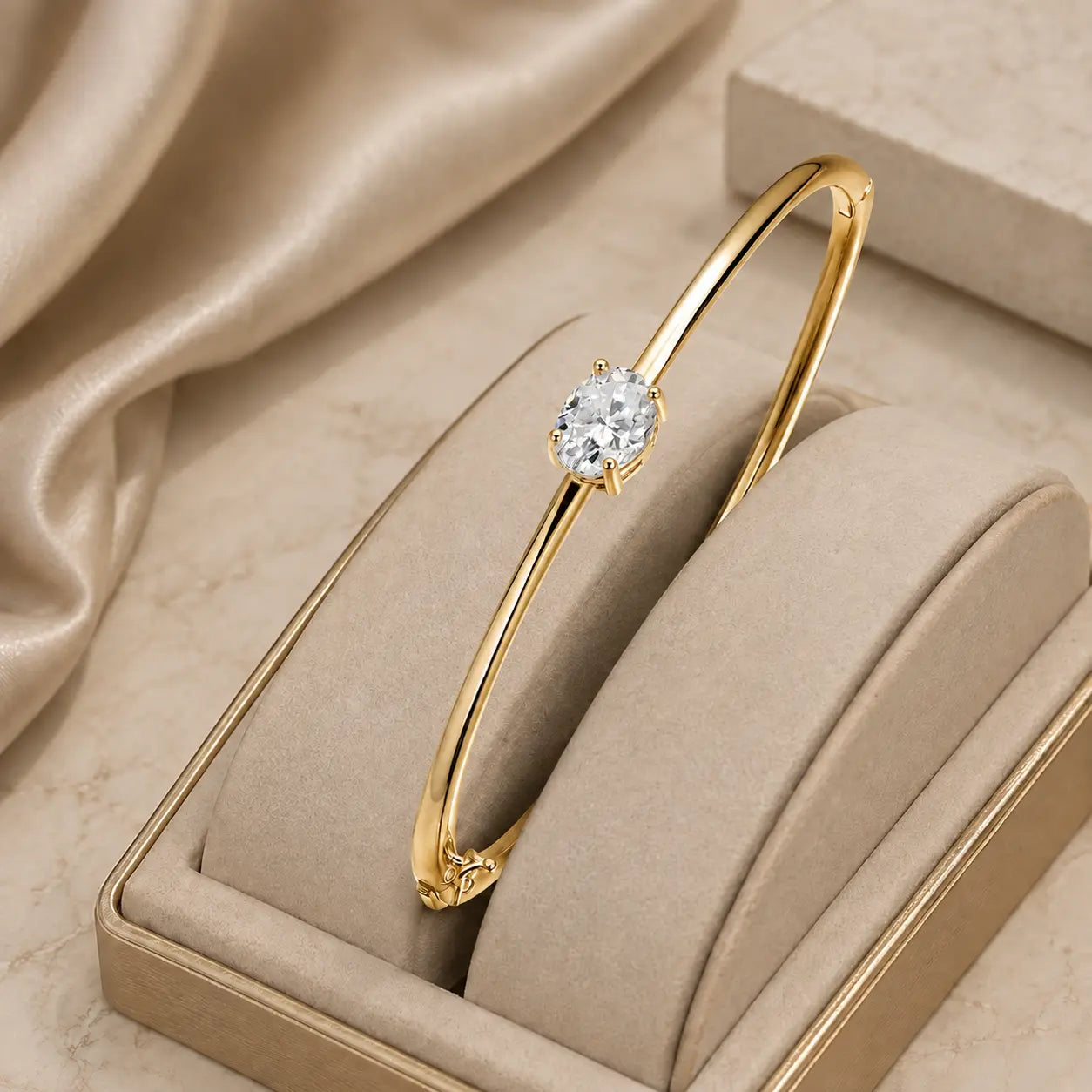 Gold-tone oval-cut moissanite bangle bracelet for women displayed in an elegant beige jewelry box.
