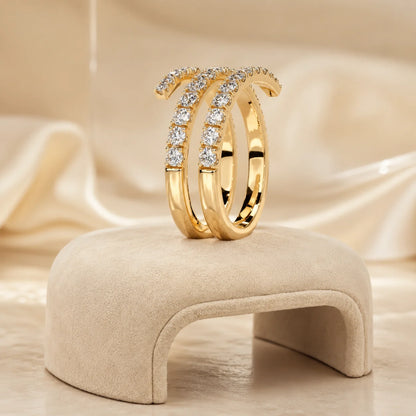 Gold three-row moissanite wrap ring displayed upright on a soft beige jewelry stand with a warm satin background.