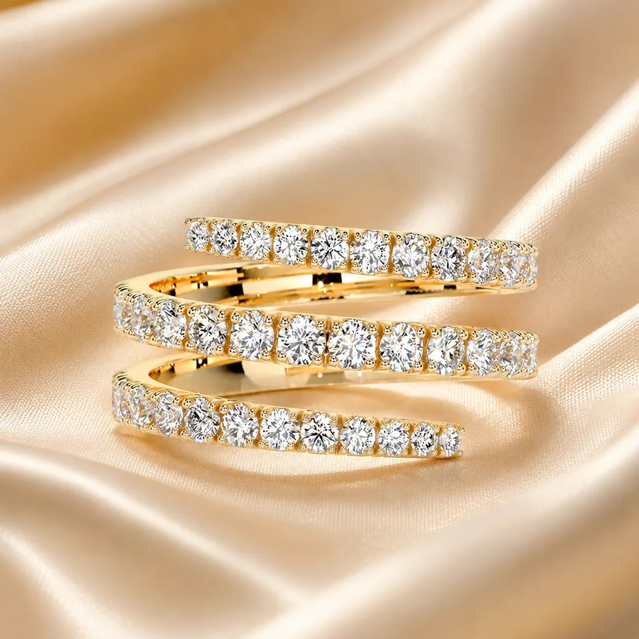 Gold three-row moissanite wrap ring with brilliant round stones displayed on elegant champagne satin.