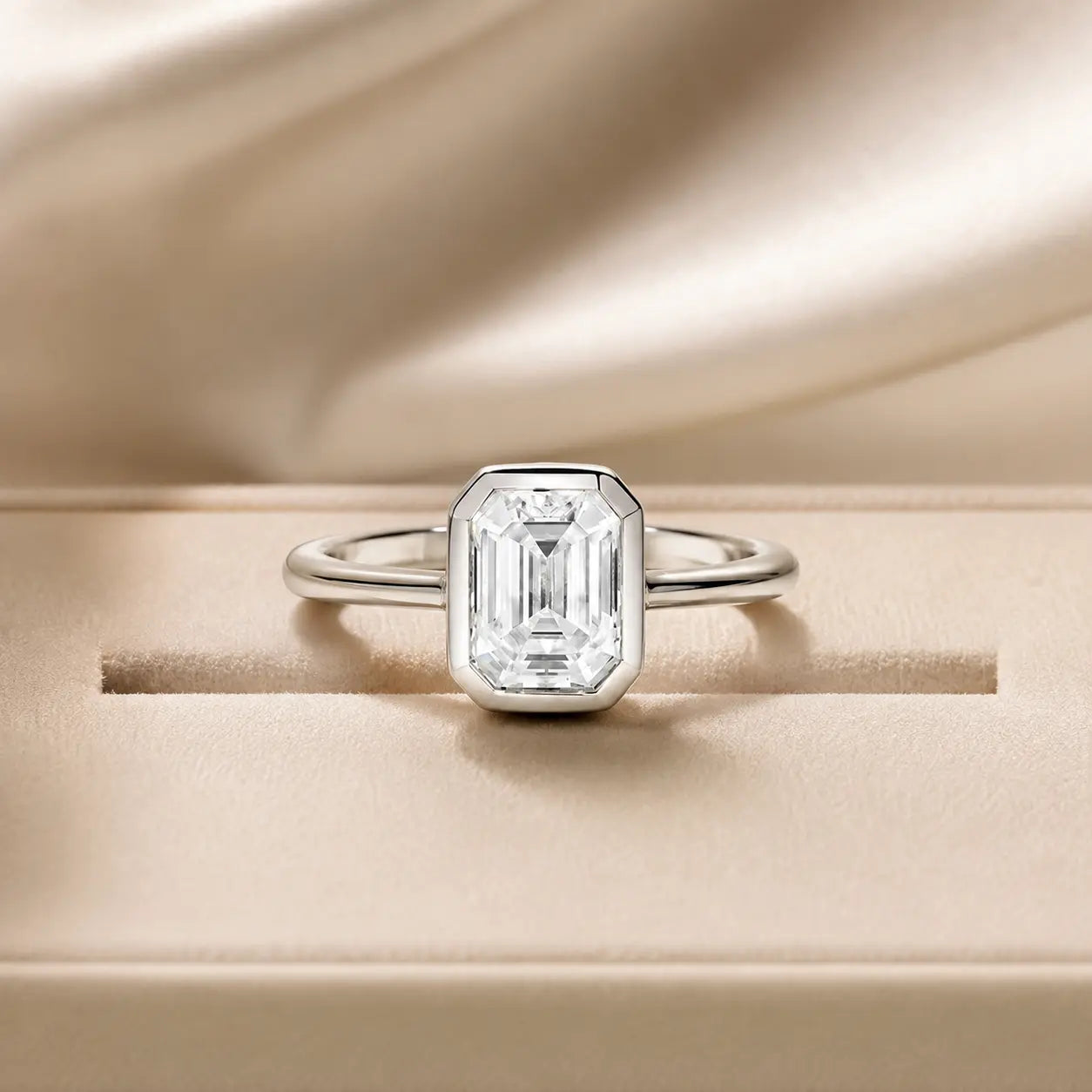 Front view of the Hadley™ 2CT Emerald-Cut Moissanite Engagement Ring displayed on a soft beige jewelry stand.