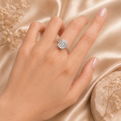 Close-up of the Hadley™ 2CT Emerald-Cut Moissanite Engagement Ring worn on a woman’s hand against a soft satin background.