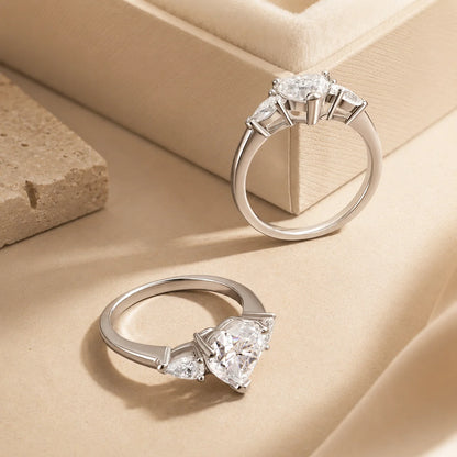 Front and side views of a heart-cut moissanite ring showing the elevated prong setting and polished silver band.