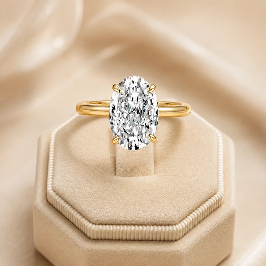 Gold Marlowe™ Oval Moissanite Engagement Ring displayed on an elegant beige velvet jewelry box.