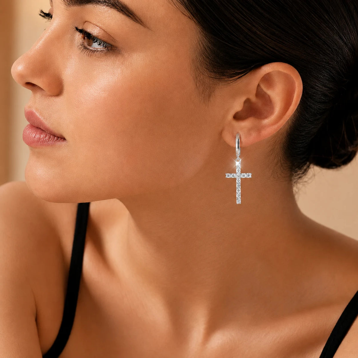 Woman wearing silver-tone moissanite cross drop hoop earrings for an elegant everyday look.