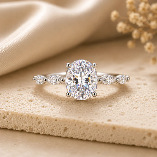 Oval-cut moissanite ring with a brilliant center stone and delicate side accents displayed on beige stone.