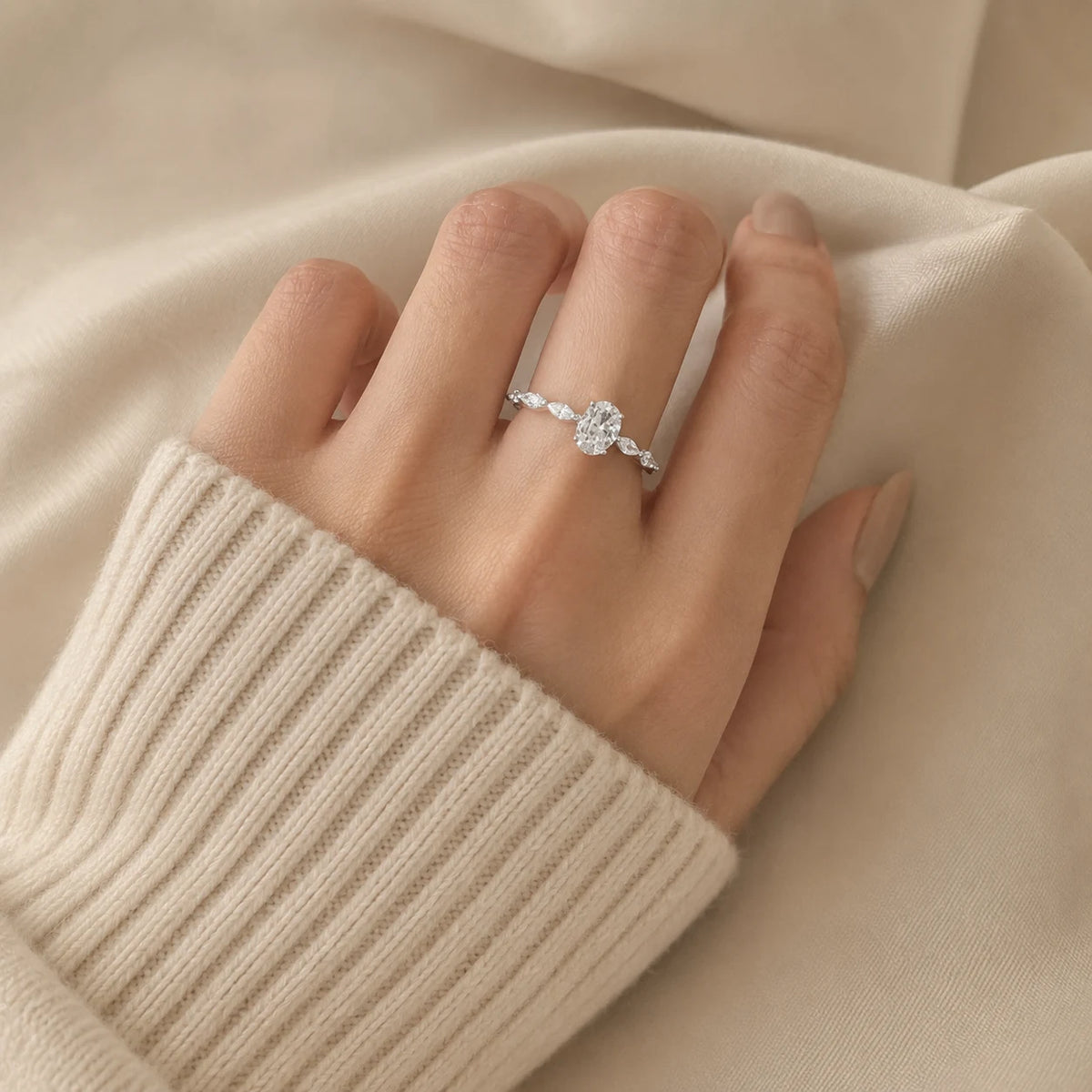 Woman wearing an oval-cut moissanite engagement ring with sparkling side stones on a polished silver band.