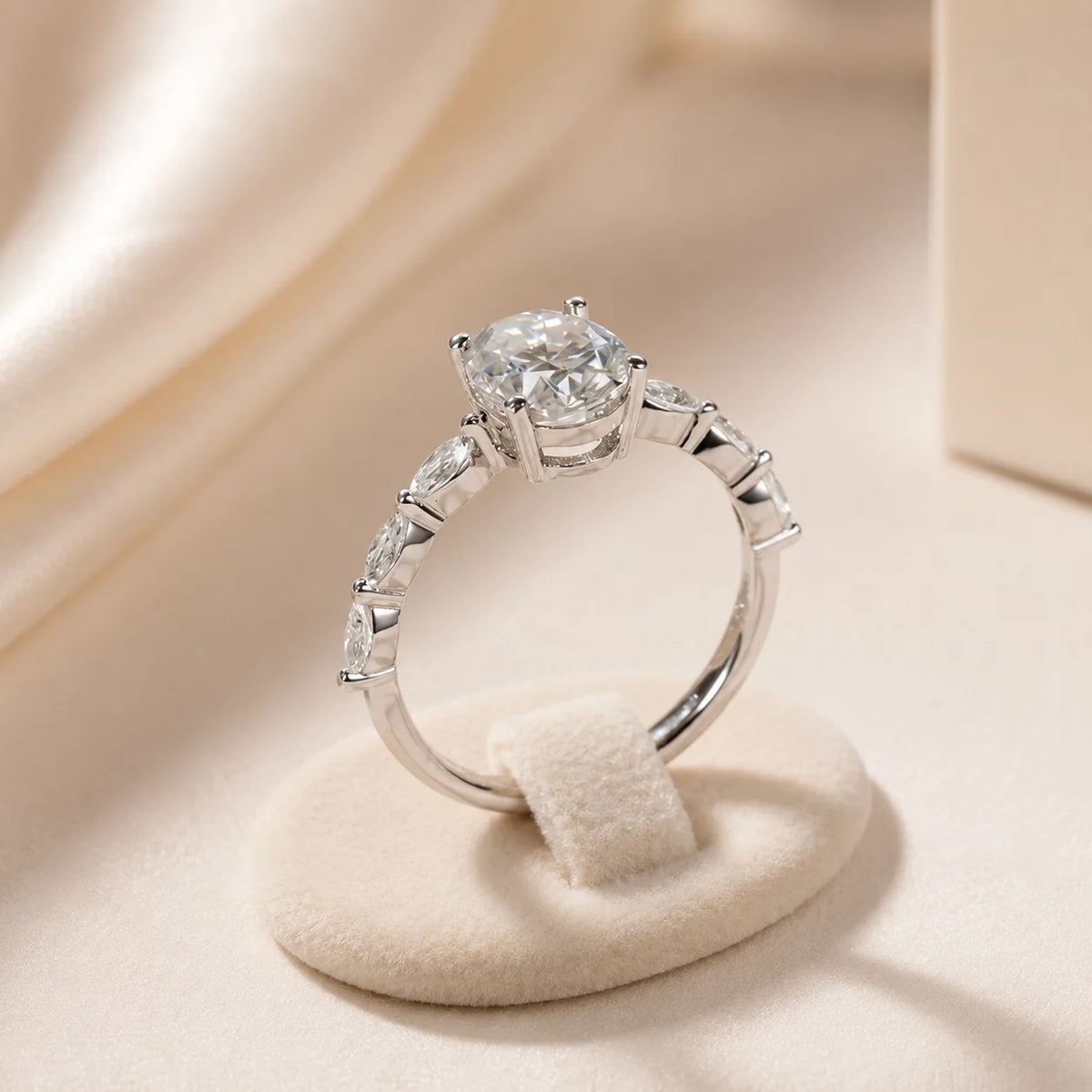 Side profile of an oval moissanite engagement ring showing the raised center setting and stone-accented band.