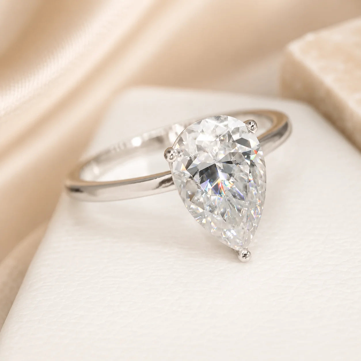 Close-up of a pear-cut moissanite solitaire engagement ring highlighting the brilliant center stone and elegant silver band.