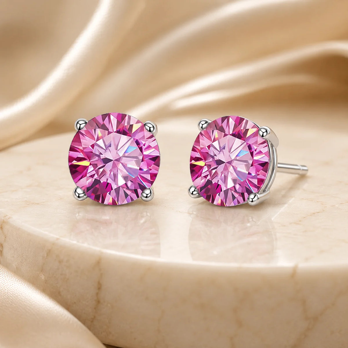 Eloryva pink round-cut gemstone stud earrings displayed on an elegant warm beige surface.