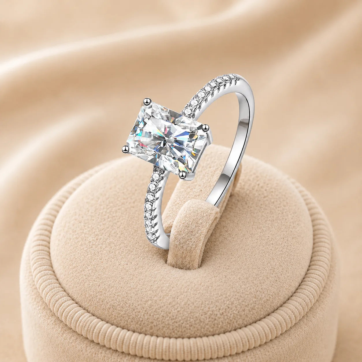 Angled view of a radiant-cut moissanite engagement ring highlighting the center stone, raised setting and pavé band.