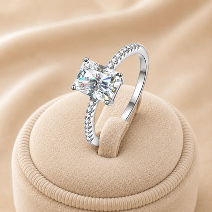 Angled view of a radiant-cut moissanite engagement ring highlighting the center stone, raised setting and pavé band.
