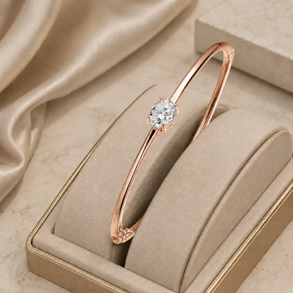 Rose gold-tone oval-cut moissanite bangle bracelet for women with a brilliant solitaire center stone.