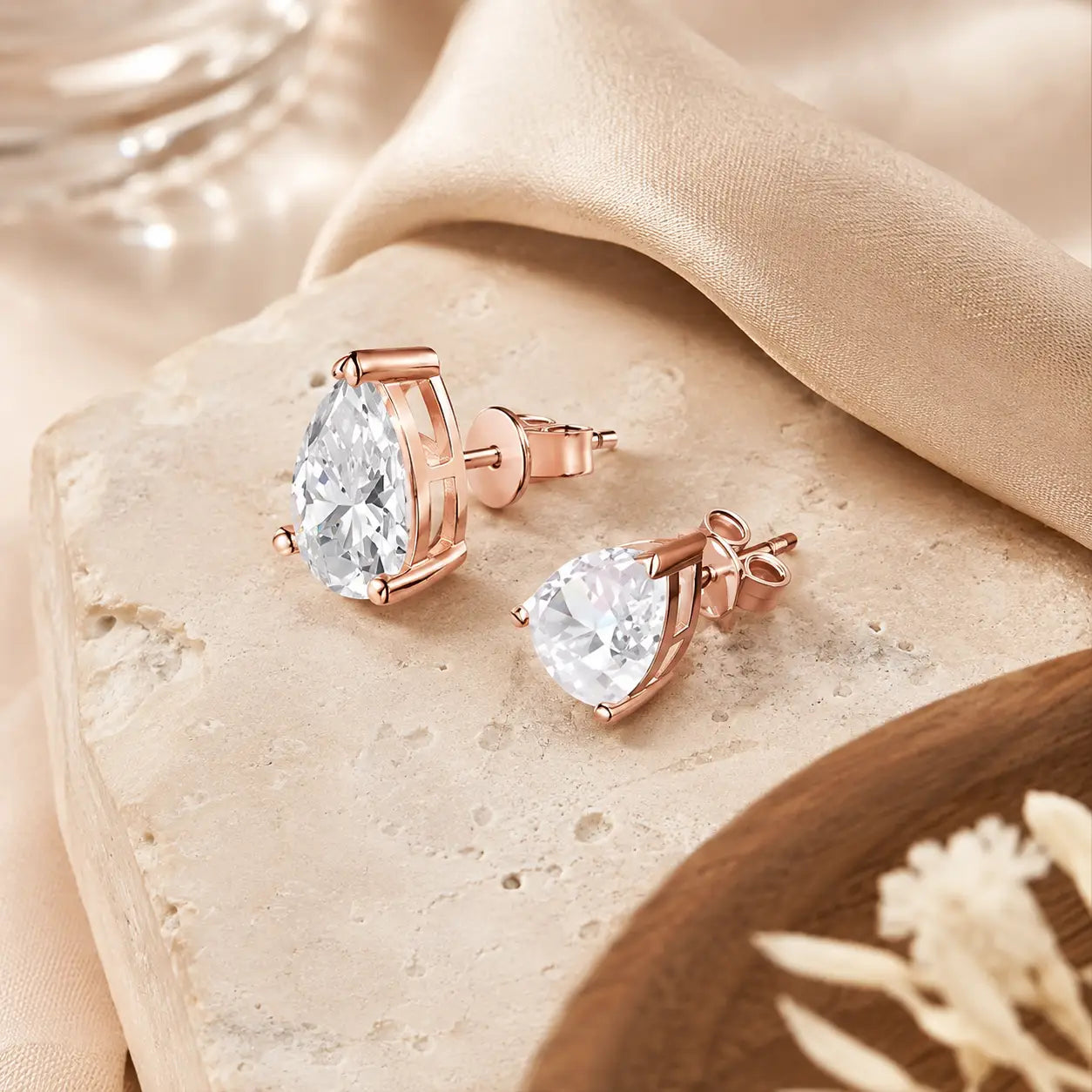 Angled view of rose gold pear-cut moissanite stud earrings showing the stone settings, posts and butterfly backs.