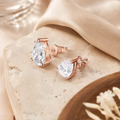 Angled view of rose gold pear-cut moissanite stud earrings showing the stone settings, posts and butterfly backs.