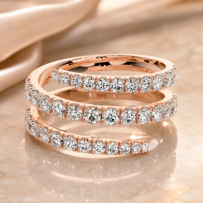 Rose gold three-row moissanite wrap ring with sparkling round stones displayed against a soft satin background.