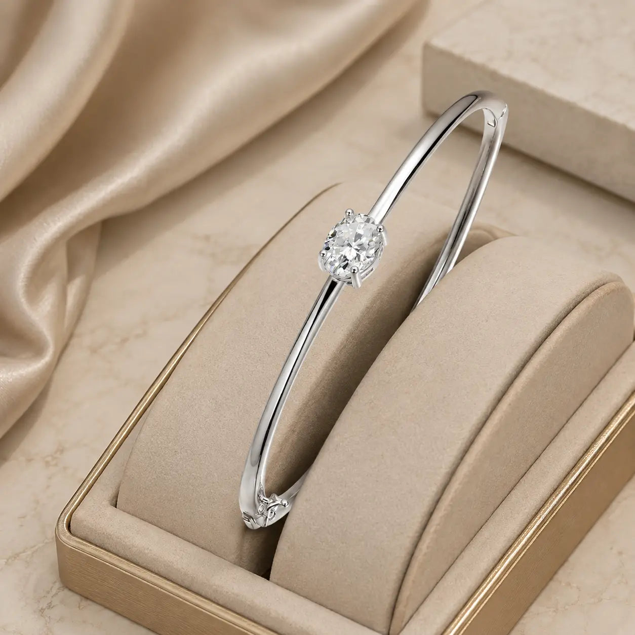 Silver oval-cut moissanite bangle bracelet displayed in a beige jewelry box with soft luxury styling.