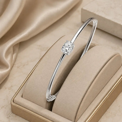 Silver oval-cut moissanite bangle bracelet displayed in a beige jewelry box with soft luxury styling.