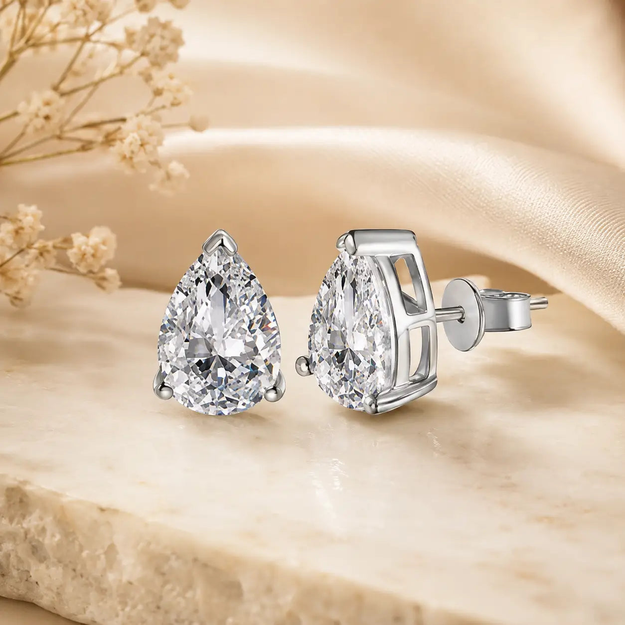 Silver pear-cut moissanite stud earrings featuring brilliant pear-shaped stones in elegant prong settings.