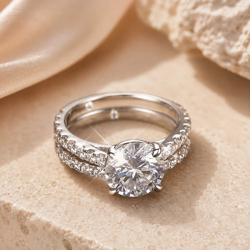 Sutton™ round moissanite engagement ring paired with a pavé wedding band and displayed on a warm beige stone surface.