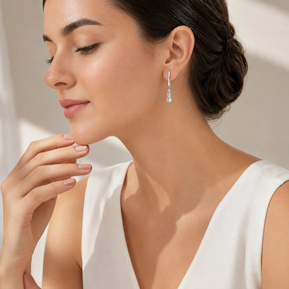 Woman wearing elegant sterling silver huggie earrings with graduated three-stone drops.