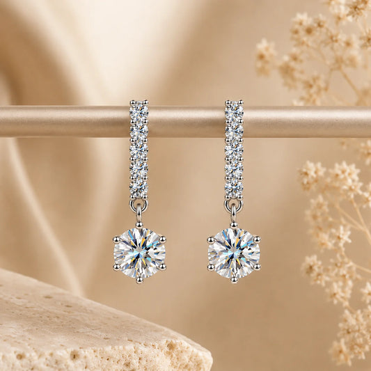 Valenne™ 2CT Moissanite Drop Stud Earrings displayed on a beige jewelry stand with sparkling round moissanite drops.