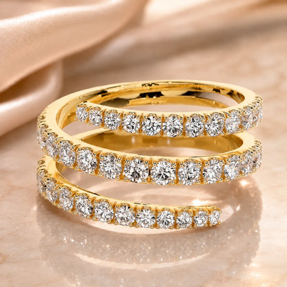 Yellow gold three-row moissanite ring featuring three curved bands of brilliant round stones on a beige surface.