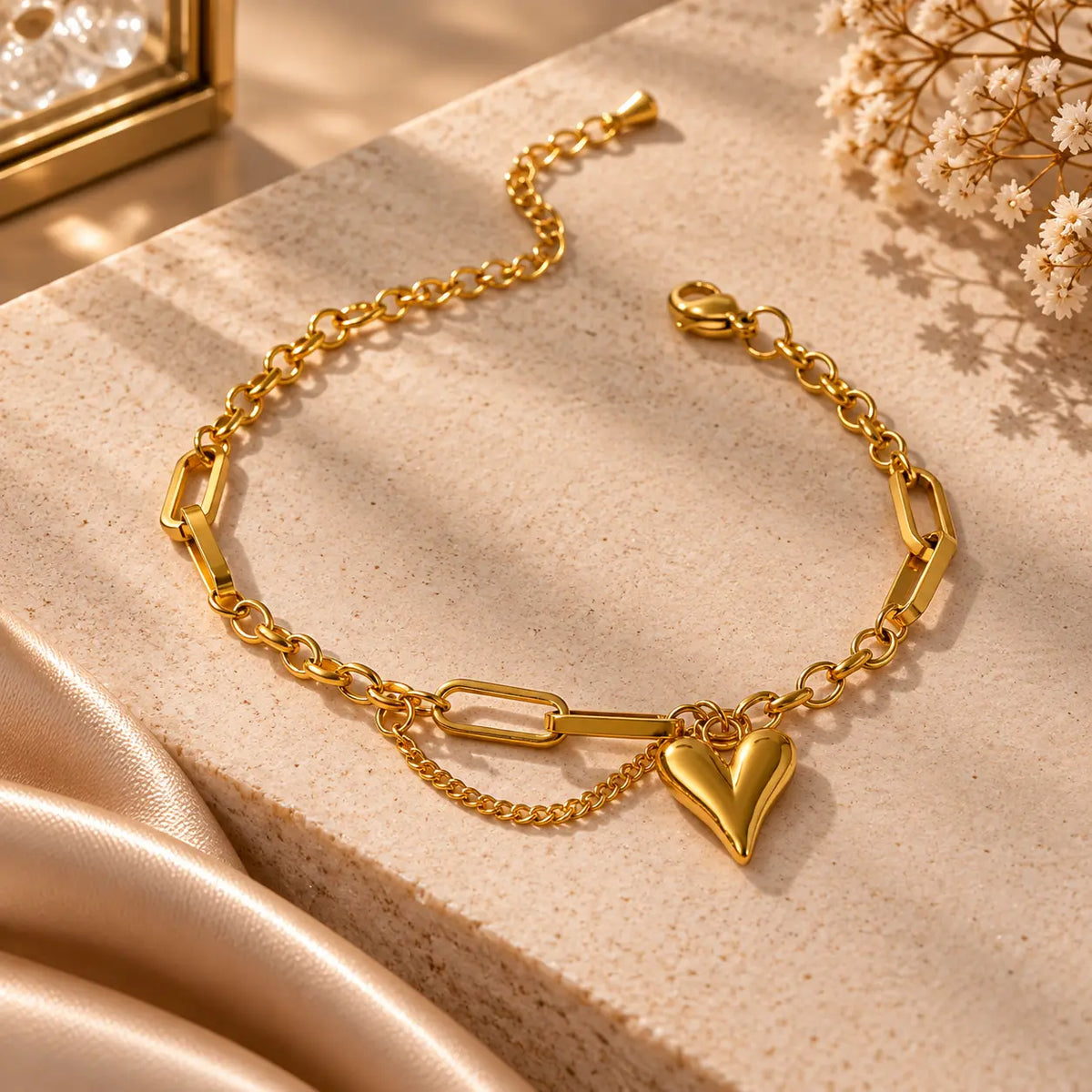 Gold tone heart charm link bracelet styled on a warm beige jewelry display
