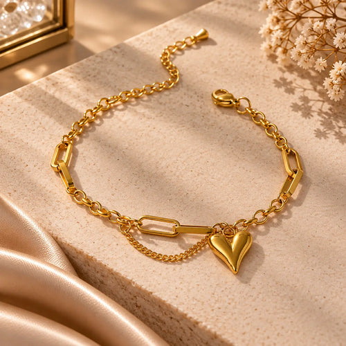 Gold tone heart charm link bracelet styled on a warm beige jewelry display