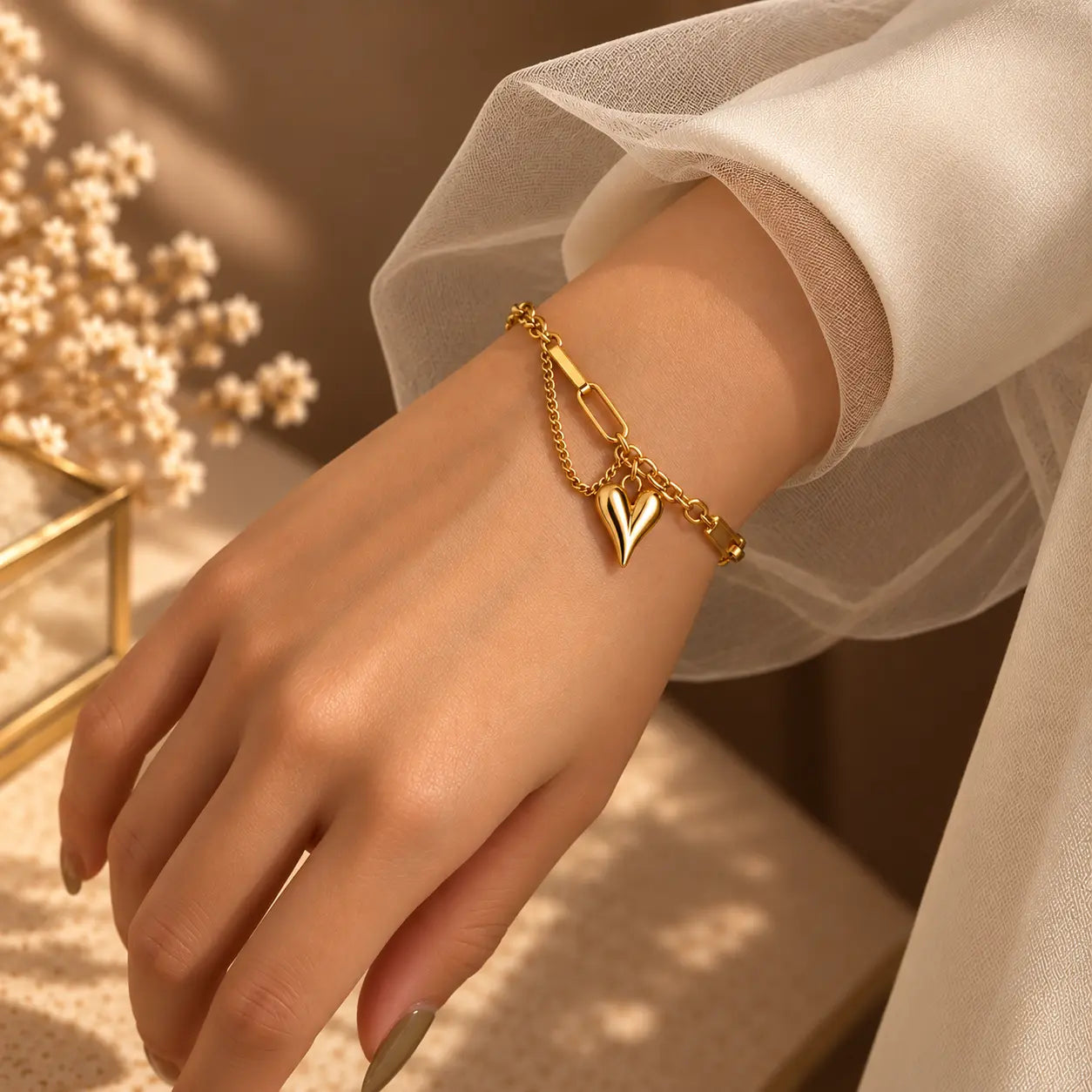 Gold tone heart link bracelet worn by a woman in a soft neutral outfit