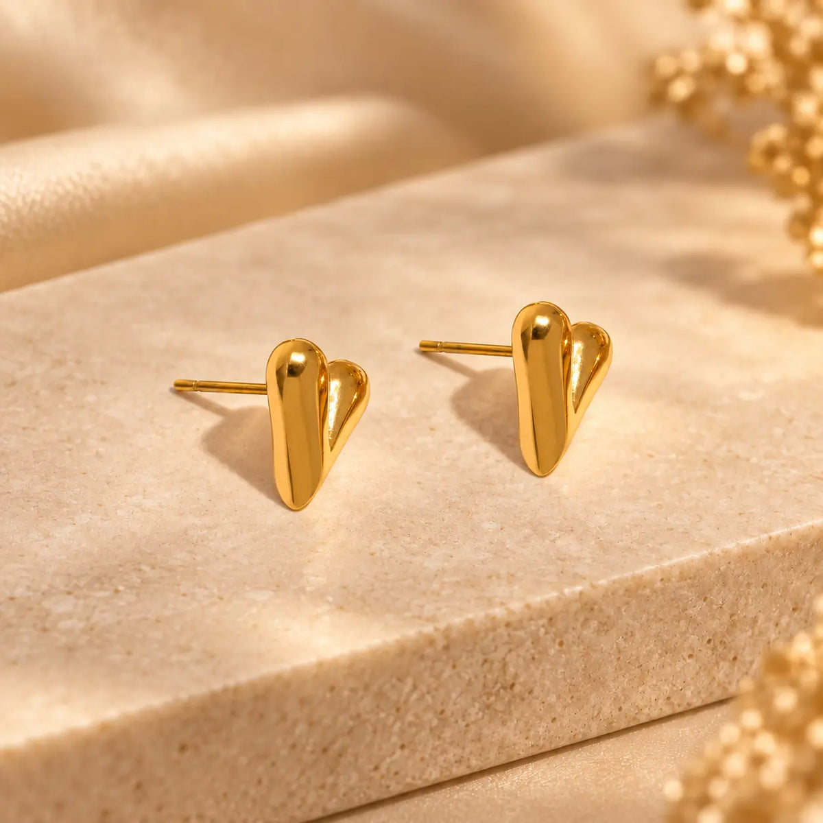 Gold heart stud earrings with a sleek polished finish