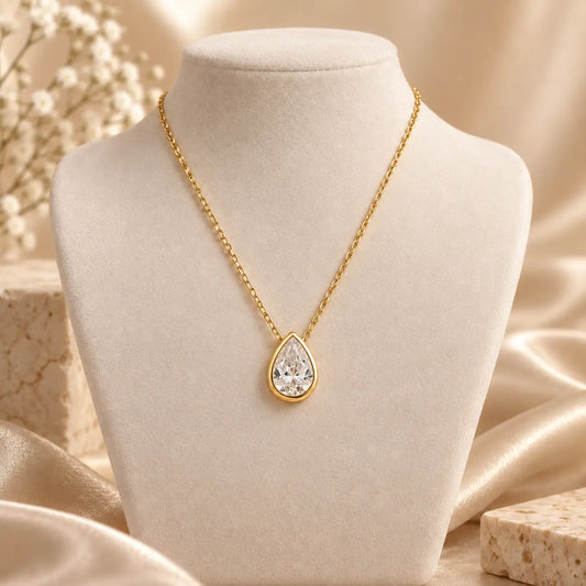 Gold tone pear cut moissanite necklace with a delicate chain on a neutral display
