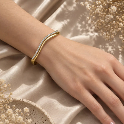 Gold-tone wave moissanite bangle bracelet for women worn on the wrist with a refined everyday jewelry look.