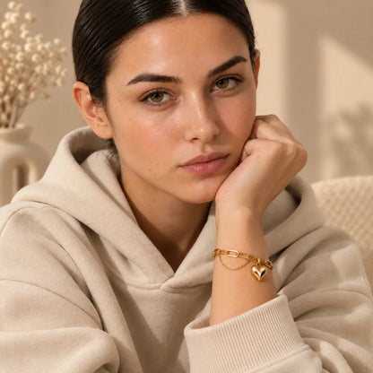 Woman styling a delicate heart charm bracelet with a casual neutral outfit