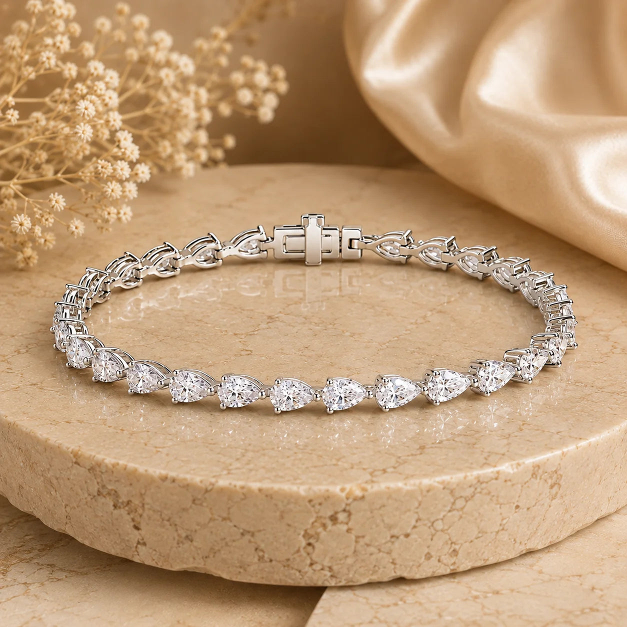 Front view of the Langley™ pear-cut moissanite tennis bracelet for women with sparkling stones and a secure clasp on a beige stone surface.