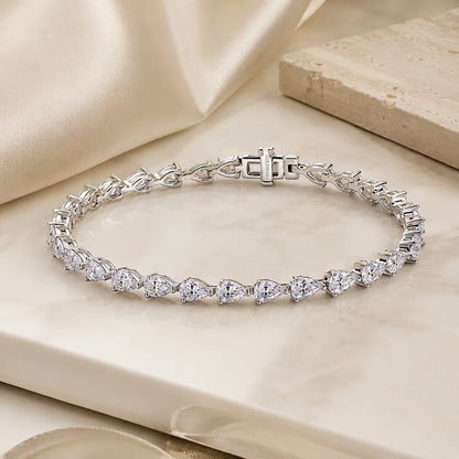 Full view of the Langley™ pear-cut moissanite tennis bracelet for women arranged in a complete circle on a beige luxury surface.